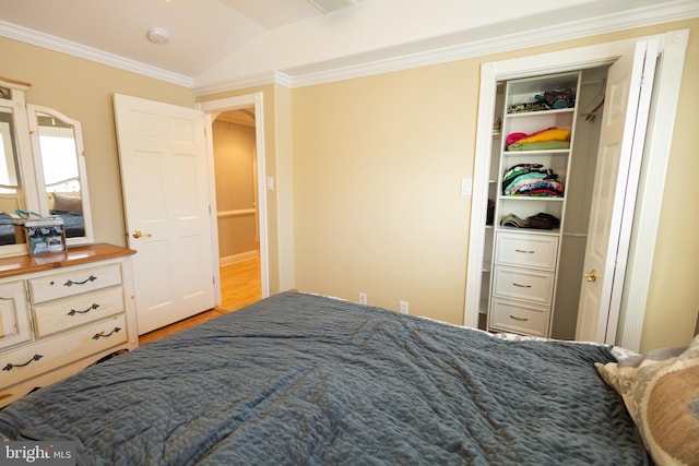 bedroom featuring ornamental molding, lofted ceiling, a closet, and light hardwood / wood-style flooring