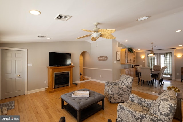 living room with ceiling fan, vaulted ceiling, and light hardwood / wood-style flooring