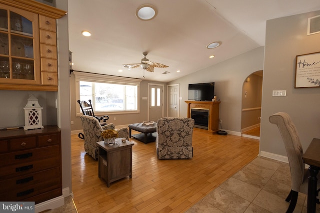 living room with vaulted ceiling, ceiling fan, and light wood-type flooring