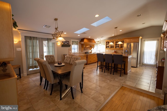 dining area featuring light tile patterned flooring, sink, and vaulted ceiling