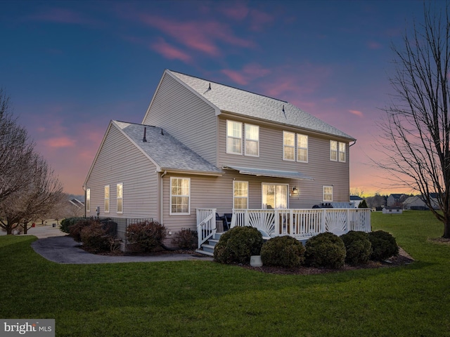 back house at dusk featuring a yard and a deck