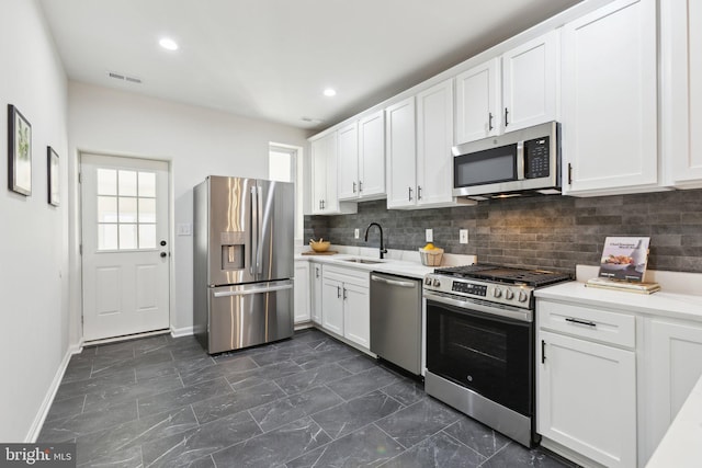 kitchen with white cabinetry, sink, tasteful backsplash, and stainless steel appliances