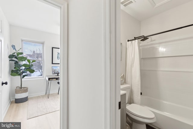 bathroom with shower / tub combo, wood-type flooring, and toilet