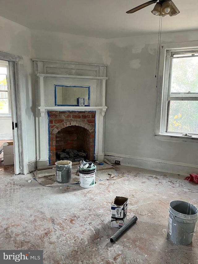 unfurnished living room featuring a brick fireplace, plenty of natural light, and ceiling fan