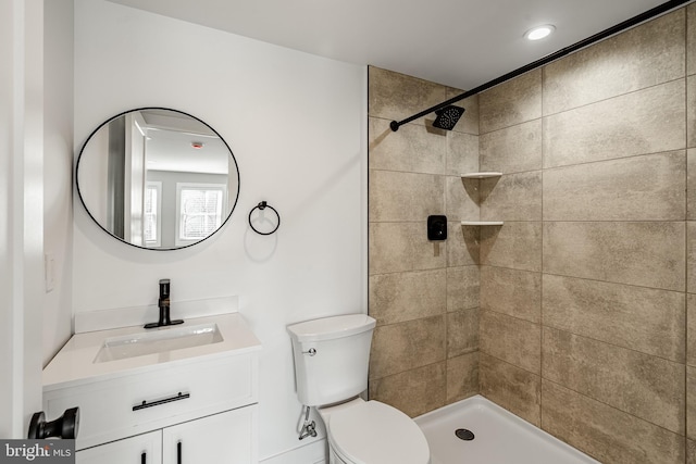 bathroom with vanity, toilet, and a tile shower