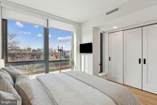 bedroom featuring floor to ceiling windows, a closet, and light wood-type flooring