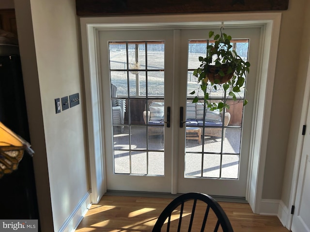 doorway with french doors, wood finished floors, baseboards, and a wealth of natural light