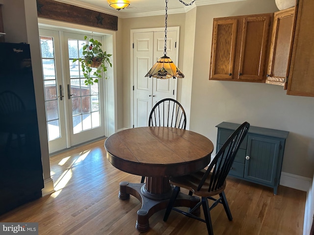 dining space with wood finished floors, a healthy amount of sunlight, and ornamental molding