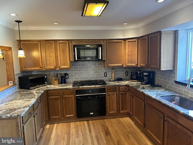 kitchen featuring a sink, brown cabinets, light wood-style floors, and black appliances