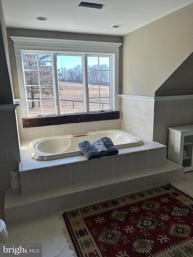 full bath with tile patterned floors, a garden tub, and tile walls