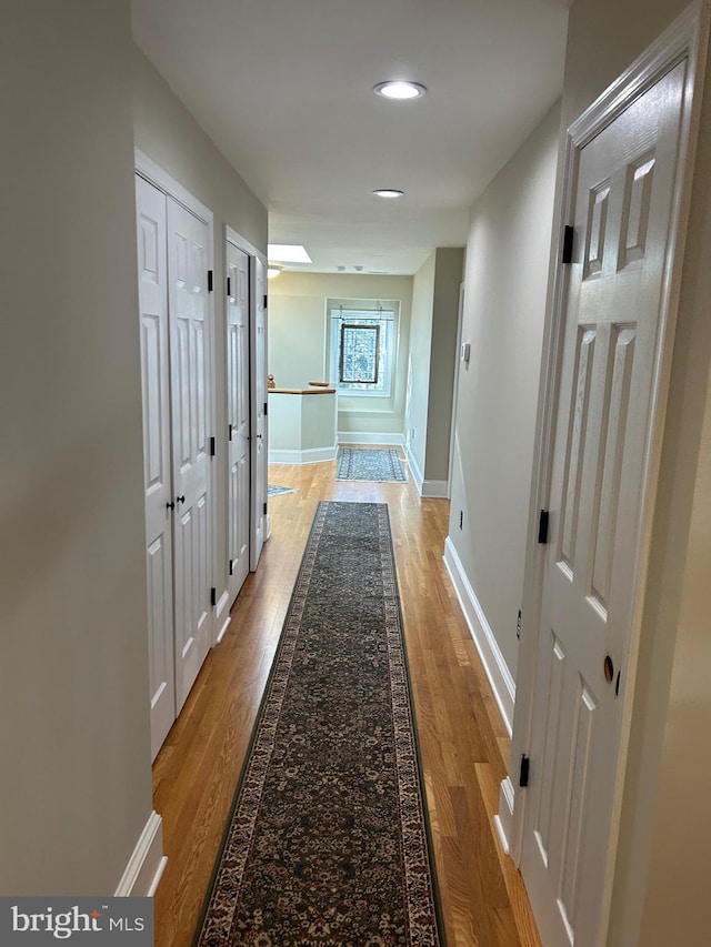 hallway with recessed lighting, baseboards, and light wood-style floors