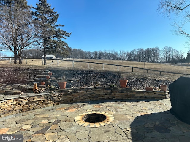 view of patio / terrace featuring a rural view, a fire pit, area for grilling, and fence