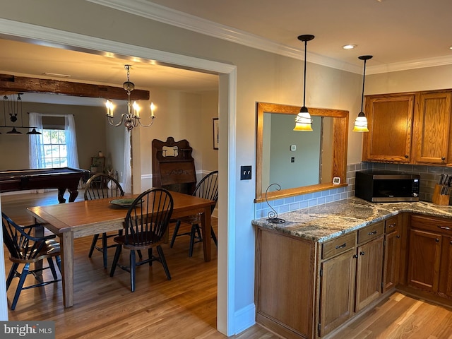 kitchen featuring light wood-type flooring, stainless steel microwave, brown cabinetry, and crown molding