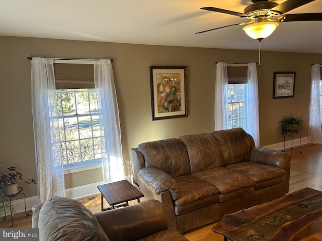 living area featuring ceiling fan, baseboards, and wood finished floors