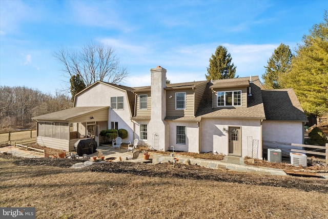 rear view of property with a shingled roof, fence, a chimney, a sunroom, and a patio