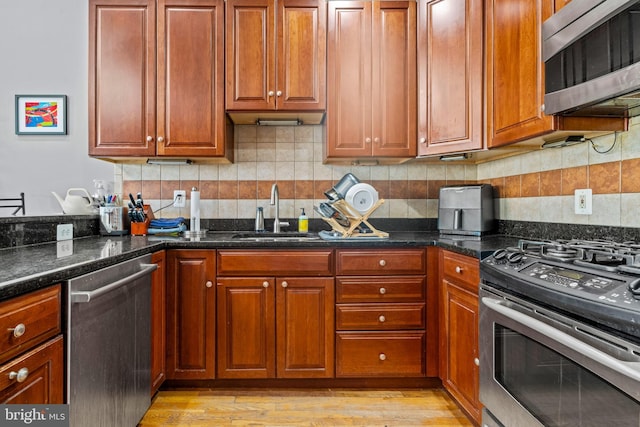 kitchen with backsplash, stainless steel appliances, sink, and dark stone counters