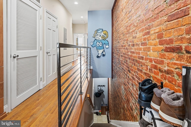 hallway with brick wall and light wood-type flooring