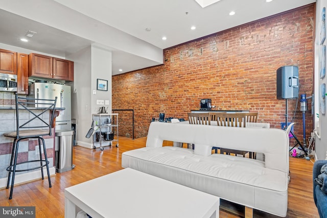 living room with brick wall and light hardwood / wood-style floors