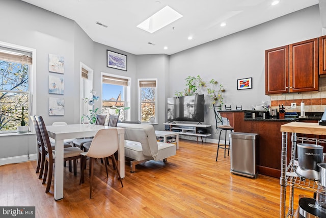 dining area featuring light hardwood / wood-style flooring and a skylight