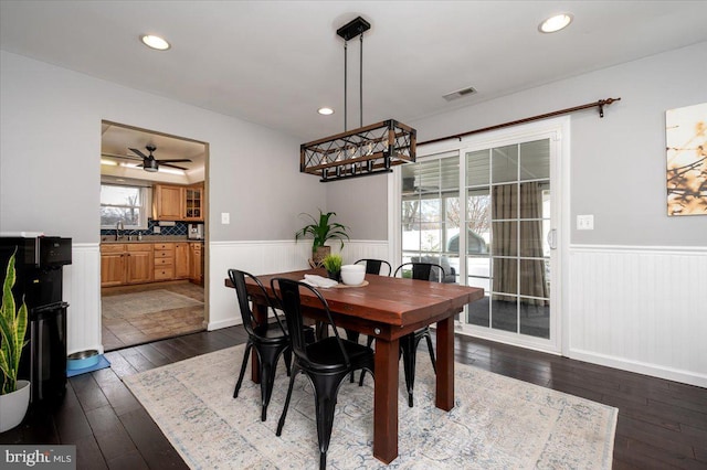 dining area with sink, ceiling fan, dark hardwood / wood-style flooring, and a raised ceiling