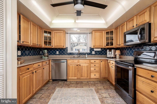 kitchen with stainless steel appliances, a tray ceiling, sink, vaulted ceiling, and decorative backsplash