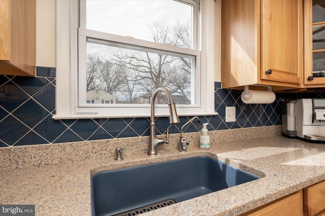 kitchen featuring decorative backsplash, sink, and light stone counters