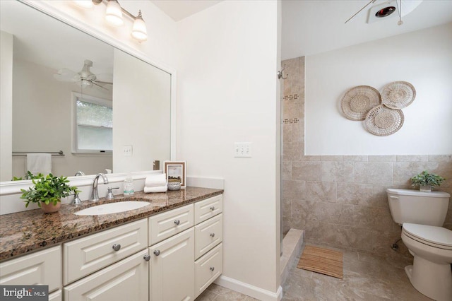 bathroom featuring tile walls, vanity, tiled shower, ceiling fan, and toilet