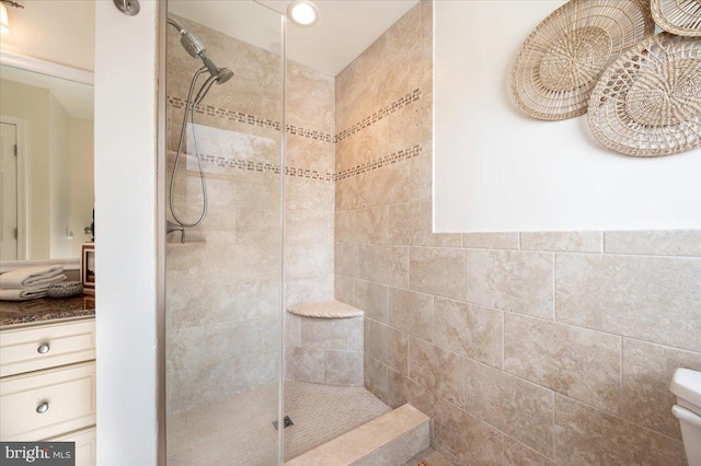 bathroom with a tile shower and vanity