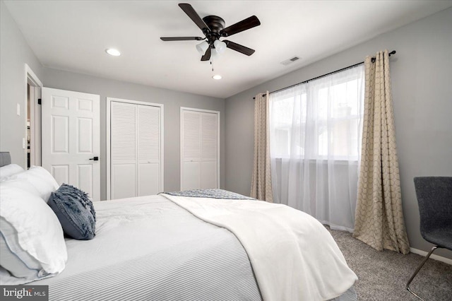 bedroom featuring ceiling fan, multiple closets, and carpet floors