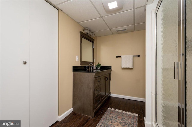 bathroom featuring a paneled ceiling, hardwood / wood-style flooring, a shower with door, and vanity