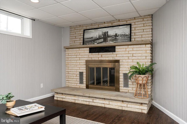 living room featuring hardwood / wood-style flooring, a paneled ceiling, and a fireplace