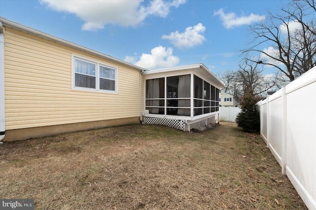 rear view of house featuring a sunroom and a lawn