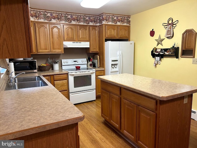 kitchen featuring sink, a center island, white appliances, light hardwood / wood-style floors, and a baseboard heating unit