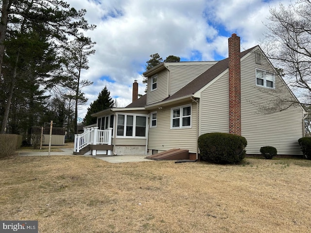 rear view of house with a sunroom and a lawn