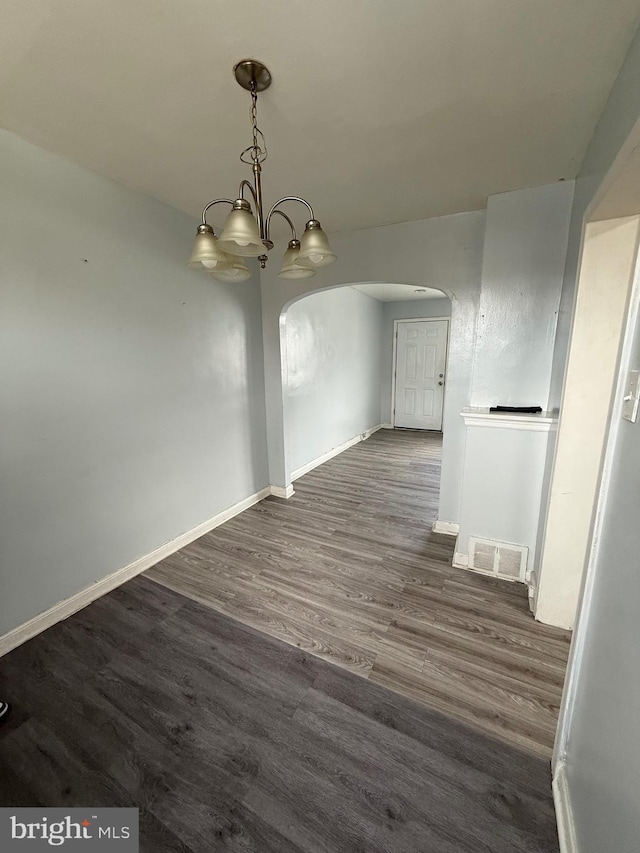 unfurnished dining area with a chandelier and dark hardwood / wood-style flooring