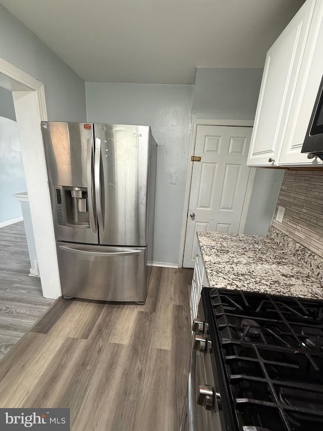 kitchen featuring stainless steel appliances, white cabinetry, dark hardwood / wood-style floors, and light stone counters