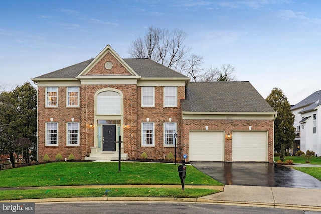 colonial home with a garage and a front lawn