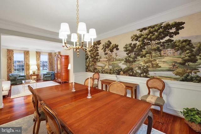 dining room with wood-type flooring, ornamental molding, and a chandelier