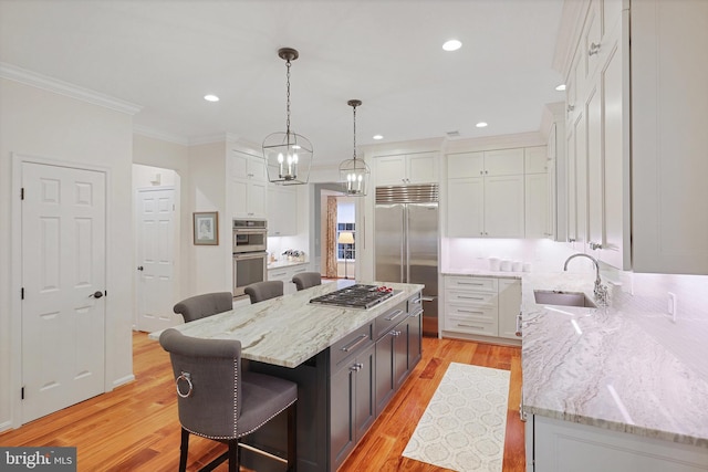 kitchen featuring sink, white cabinetry, stainless steel appliances, a kitchen island, and decorative light fixtures