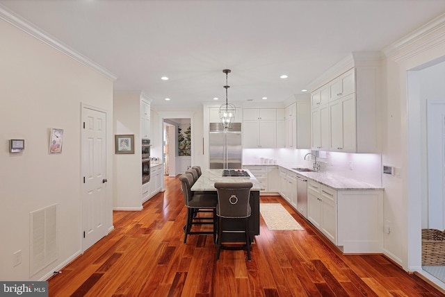 kitchen featuring appliances with stainless steel finishes, sink, a kitchen bar, hanging light fixtures, and a center island