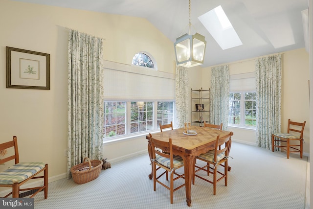 dining space featuring vaulted ceiling with skylight, carpet floors, and a notable chandelier