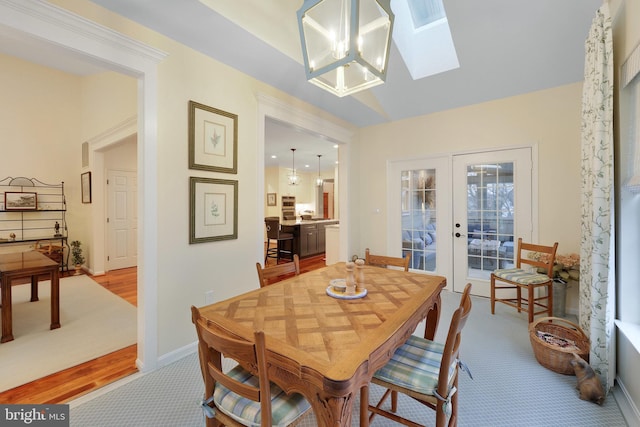 dining area featuring a skylight, french doors, and a chandelier