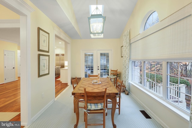 carpeted dining space with a notable chandelier and french doors