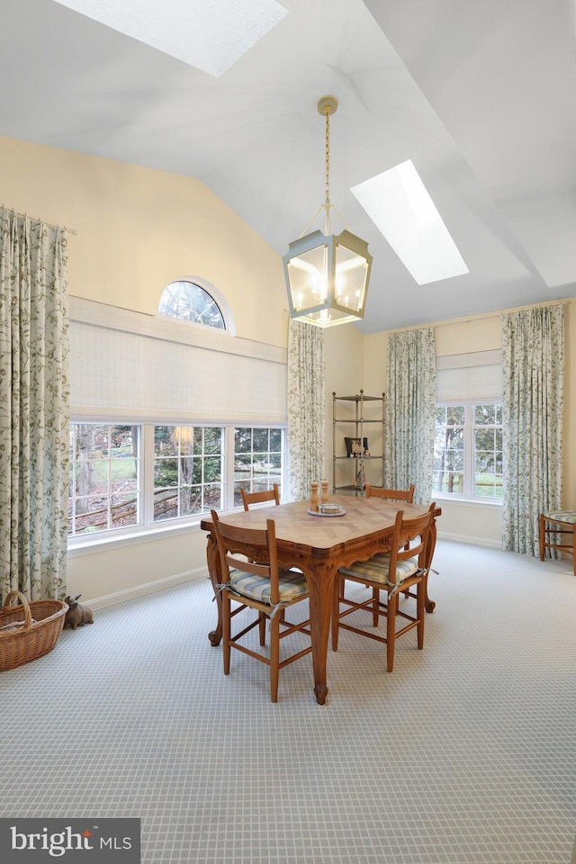 dining room featuring lofted ceiling with skylight, a chandelier, and carpet