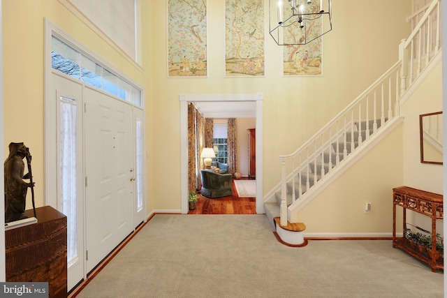 foyer featuring a notable chandelier, carpet, and a high ceiling