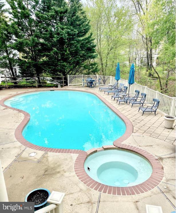 view of swimming pool featuring an in ground hot tub and a patio