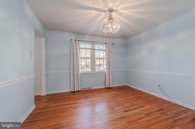 unfurnished room featuring an inviting chandelier and light hardwood / wood-style floors