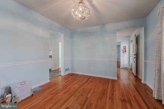 unfurnished room featuring wood-type flooring and a chandelier