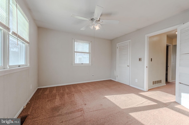 interior space featuring multiple windows, light carpet, and ceiling fan