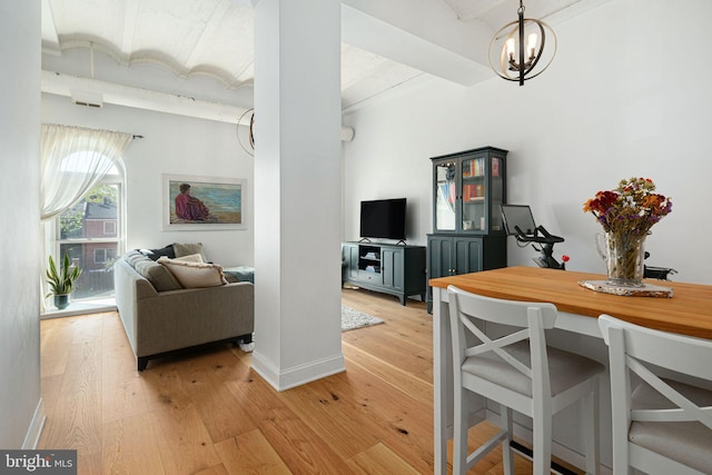 dining space featuring light hardwood / wood-style flooring, decorative columns, and a chandelier